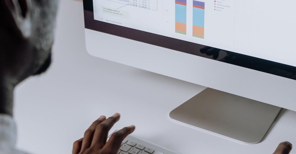 Businessman analyzing charts and data on desktop computer in office setting.